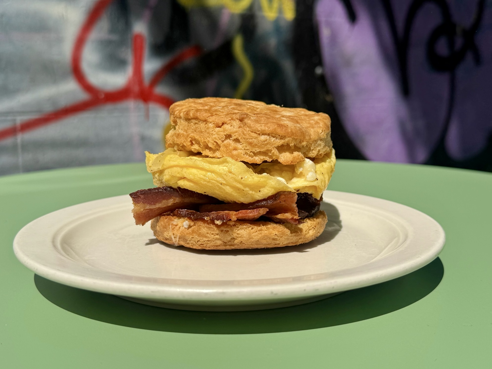Bacon, egg and cheese on a golden biscuit, on a plate at Foster Sundry.