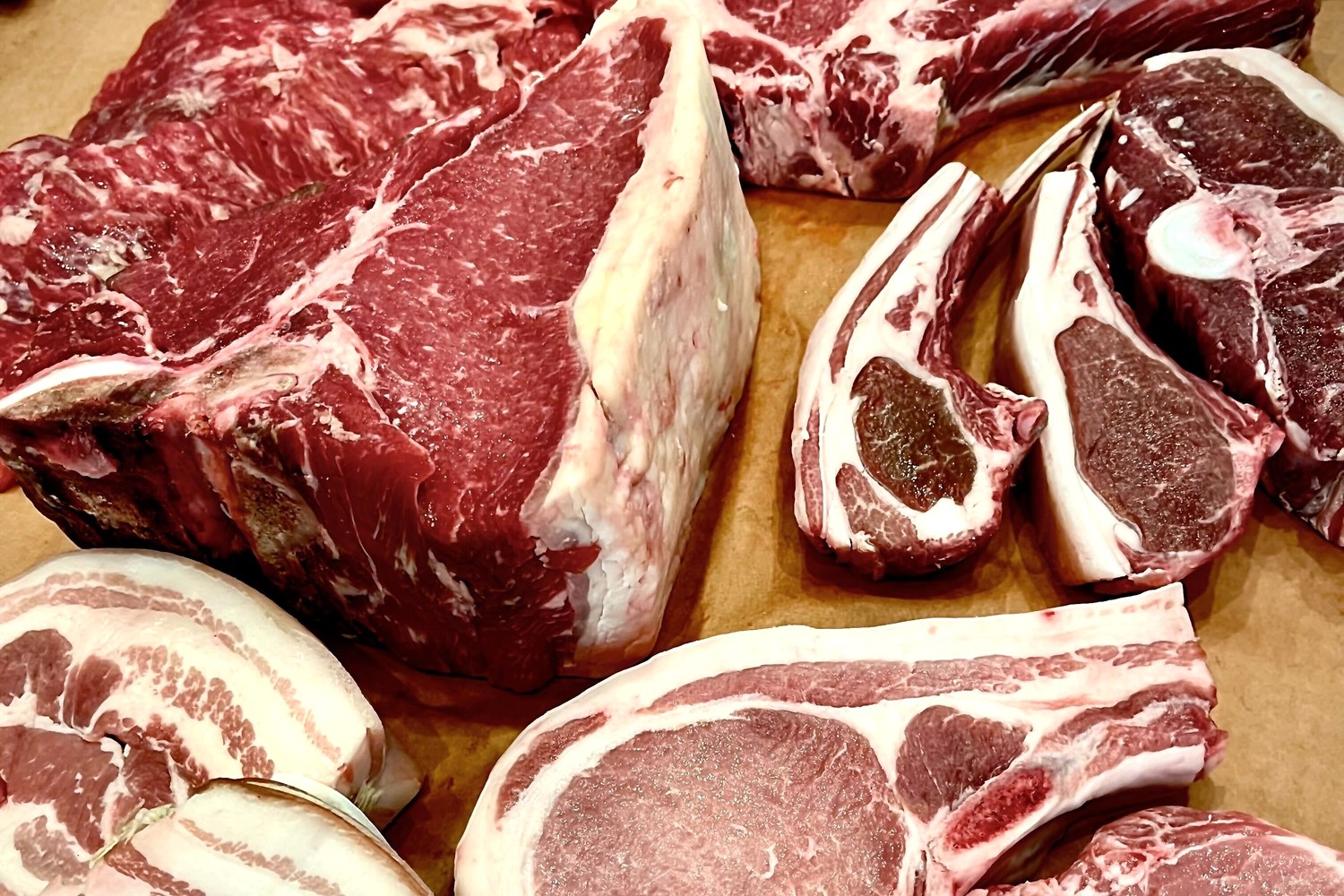 An assortment of marbled meat cuts and bone-in chops arranged on butcher paper at Foster Sundry.