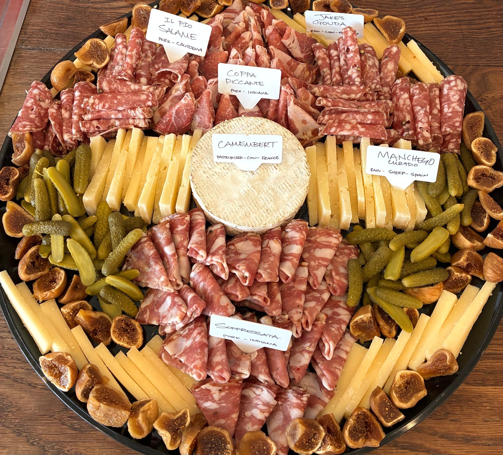 Foster Sundry cheese and charcuterie platter with sliced cheeses, rolled cured meats, cornichons and figs.